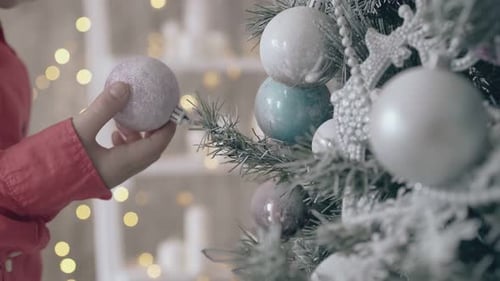 Child Decorates Christmas Tree with White Ornaments
