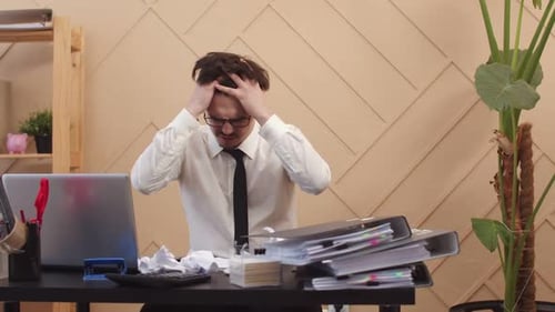 Frustrated Man Pulling Hair at Office Desk