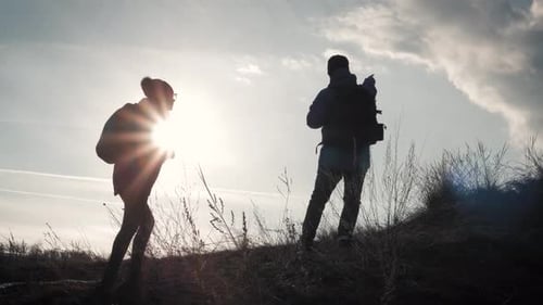 Happy Couple Man and Woman Tourist at Top of Mountain at Sunset Outdoors During a Hike. Silhouettes