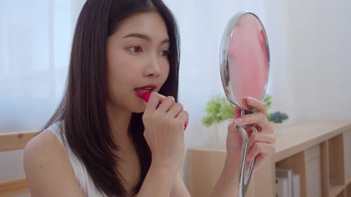Young Woman Applying Lipstick with Hand Mirror