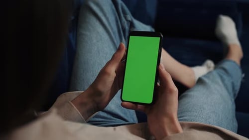 Close Up Woman at Home Using Smartphone with Green Mock-up Screen, Doing Swiping, Scrolling Gestures