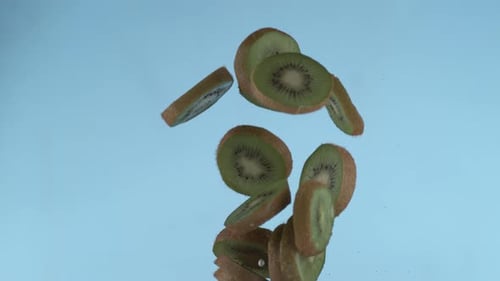 Kiwi Slices Falling on Blue Background