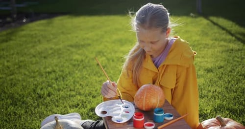 A Child Paints a Pumpkin Prepares Decorations for Halloween