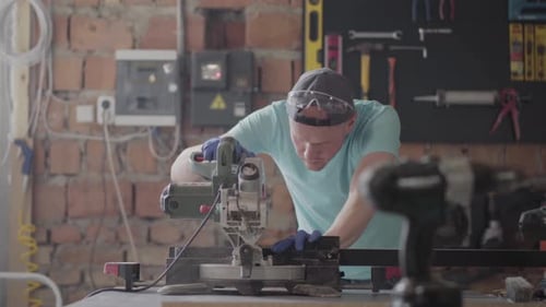 Man Cutting Wood with Miter Saw in Workshop