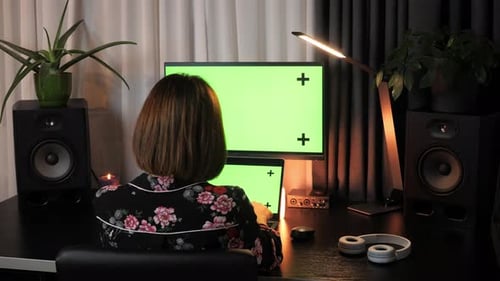Mujer trabajando en su escritorio de oficina por la noche con pantalla verde