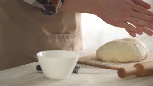 Baker Kneading Dough on a Cutting Board