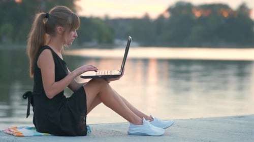 Young Woman Working Behind Laptop Sitting in Summer Park Outdoors