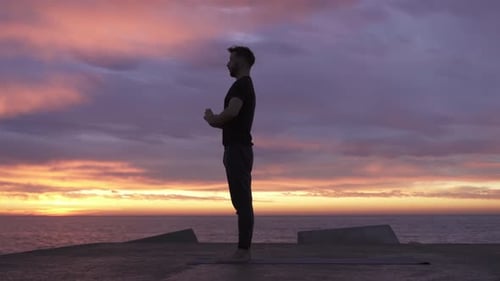 Young Athletic Man Performing Yoga Pose in Front of the Ocean at Sunrise