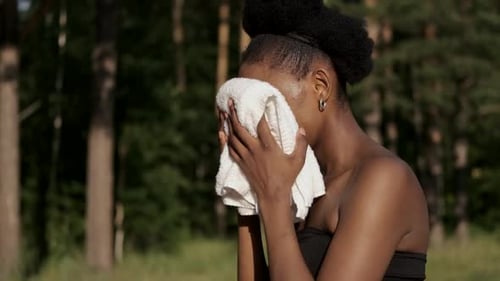 Woman Wipes Face with Towel After Workout