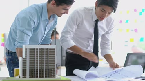 Architects working blueprint and building model