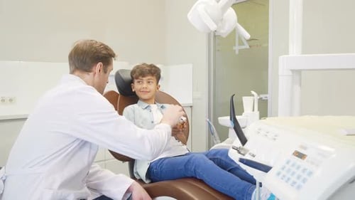 Friendly Dentist Explains Dental Model to Young Patient