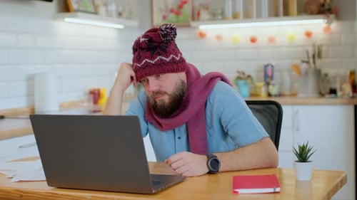 Bearded Man Works on Laptop Wearing Winter Hat