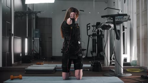 Young Woman Training Her Hands in Ems Suit in the Gym
