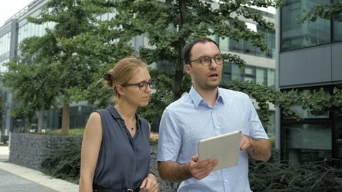 Female and Male Business People Walking Talking and Using Tablet.