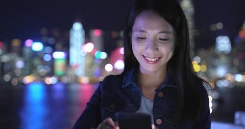 Woman Using Smartphone at Night With City Lights