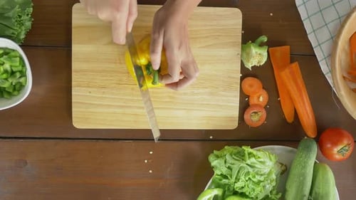Person Slicing Yellow Pepper for Cooking