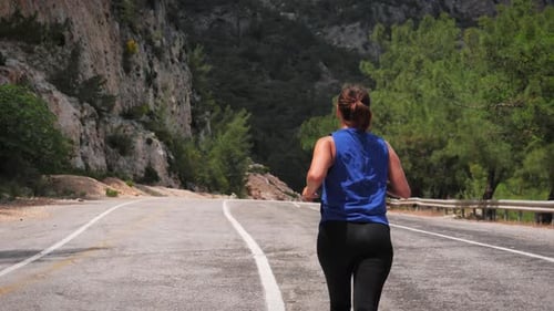 Young active woman running on mountain road.