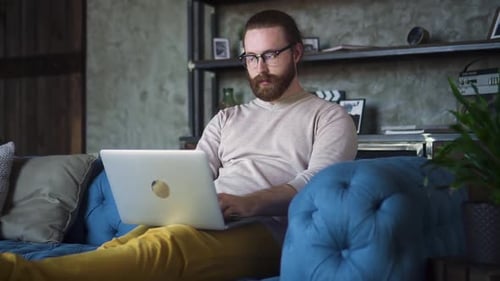Man Relaxing on Couch Working on Laptop