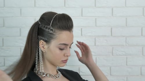 Woman Adjusting Brown Hair with Silver Chain Accessories