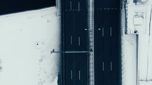 Aerial View Vertically Down the Road Bridge in Winter in Snowfall Over the Bay