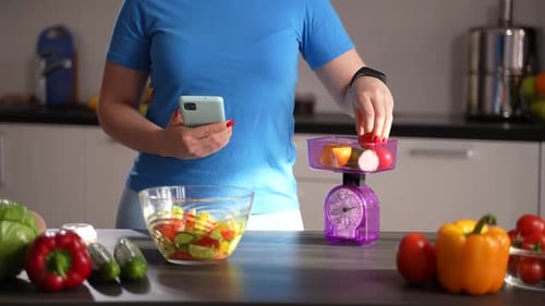 Losing Weight Female Counting Calories in Kitchen