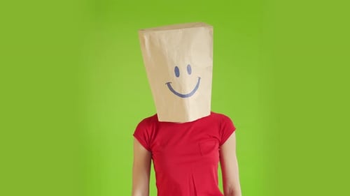 A Crazy Woman is Gesturing with a Cardboard on Her Head with Smiley Face on a Green Screen Chromakey