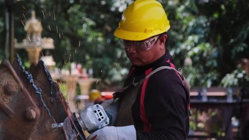 Man work in home workshop with angle grinder, goggles and construction gloves.