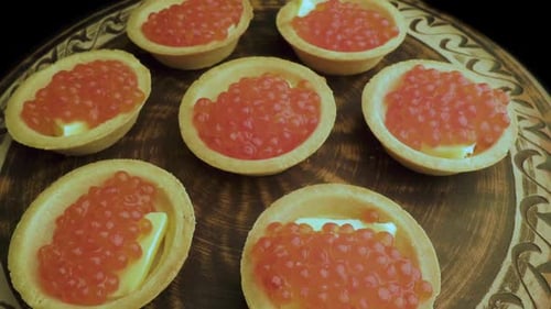Red Caviar Is Put with a Spoon on Tartlets. Preparation of Snacks with Red Caviar. Top View