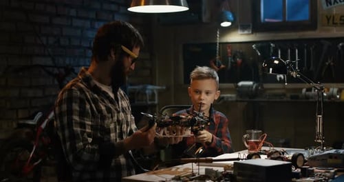 Father and Son Assembling Drone in Workshop