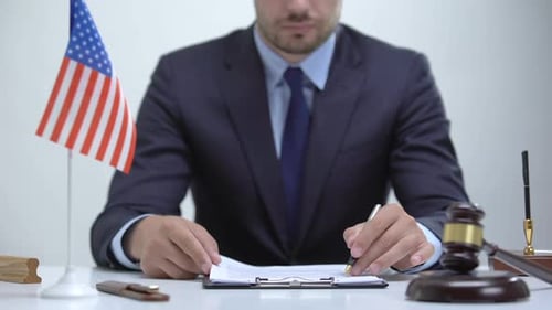 Professional Signs Legal Documents in Office with American Flag