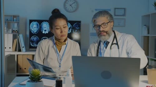 Asian Woman and Caucasian Man Doctors Analyzing Lungs Xray Image and Talking Working in Hospital at