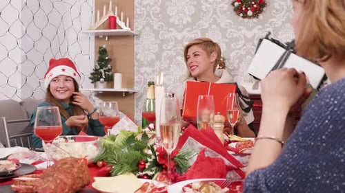 Family Exchanging Christmas Gifts at Dinner Table