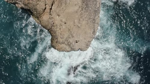 Tourists Laying Down on Top of Cliff Surrounded By Sparkling Ocean Waters, Indonesia