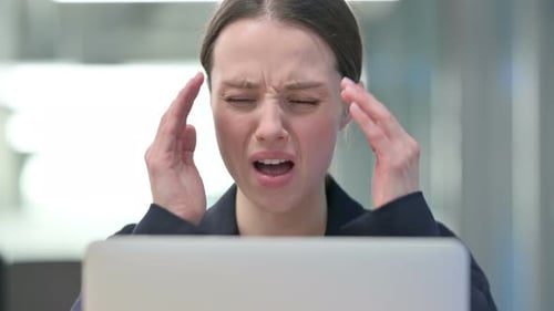 Woman Massaging Temples Due to Headache at Work