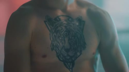 Muscular Man Flexing with Wolf Tattoo on Chest