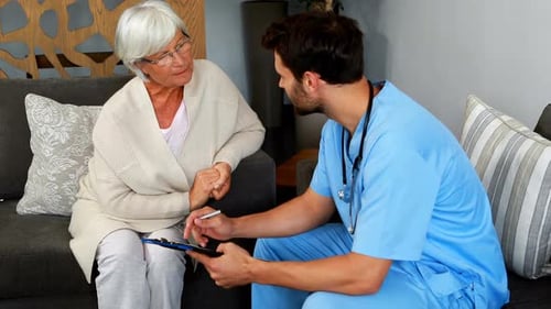 Doctor and senior woman discussing over clipboard