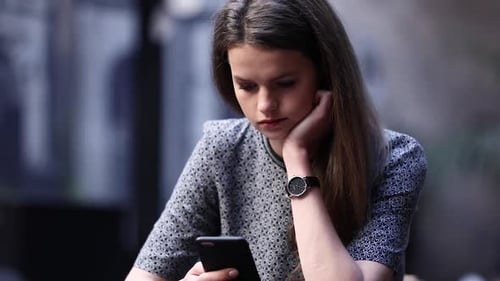 Upset Young Woman With Mobile Phone At Restaurant