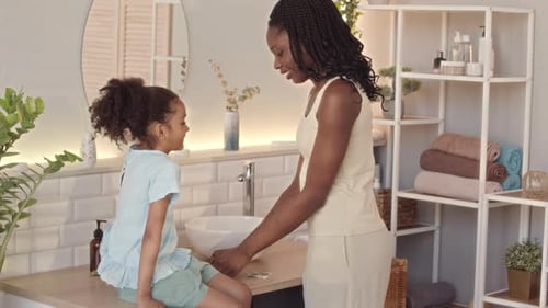 Woman Applies Bandage to Young Girl's Cheek