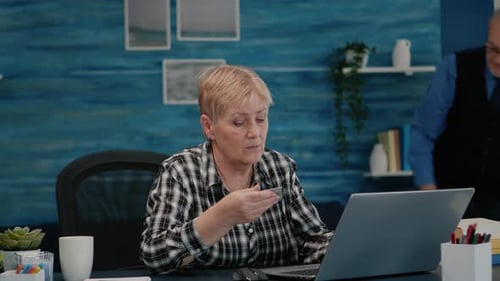 Senior Woman Using Laptop with Credit Card at Home