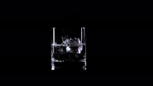 Ice Cubes Dropping Into a Glass of Water