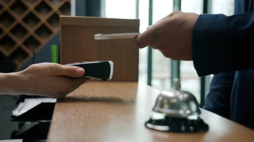 Closeup of Male Hand Making Online Payment with Smartphone Then Taking Key Card at Hotel