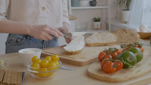 Woman Spreads Cheese on Bread Slice for Sandwich