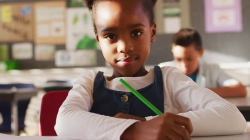 Young Girl Writing at Her Desk in Classroom