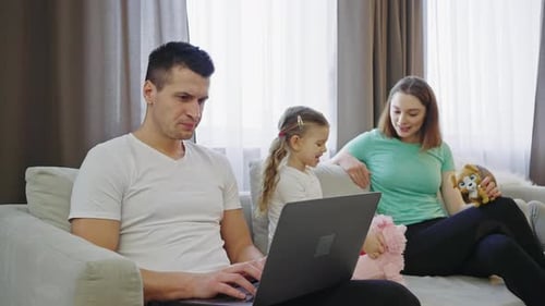 Father Working on Laptop His Wife Daughter and Son Playing Toys Nearby Slow Motion