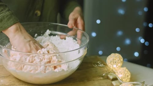 Hands mixing dough in glass bowl, holiday baking