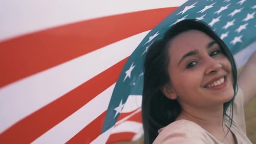 Woman Smiles Holding American Flag in Open Field