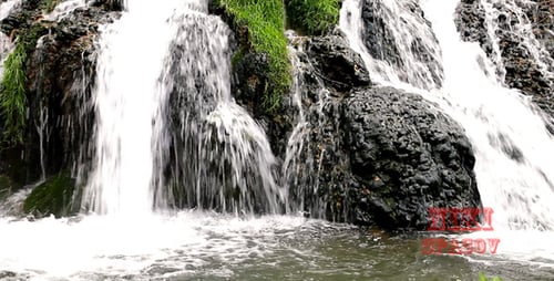 Scenic Waterfall Flowing Through Green, Rocky Landscape