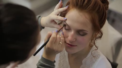 Hochzeits-Maskenbildner macht ein Make-up für die Braut im Schleier