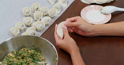 Hands Preparing Tasty Dumplings on Table