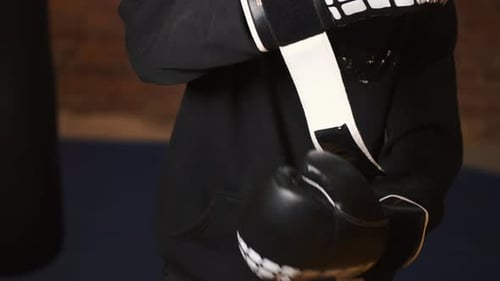 Person Secures Black Boxing Gloves for a Workout